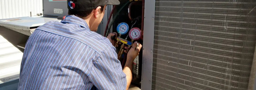 HVAC technician servicing a condenser unit in Picayune